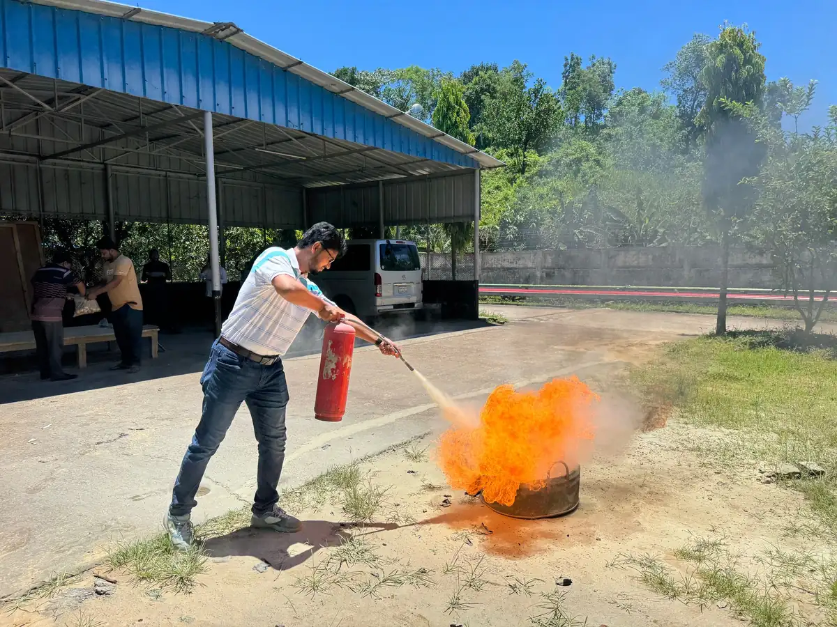 Salarié éteignant un feu d'entraînement avec un extincteur